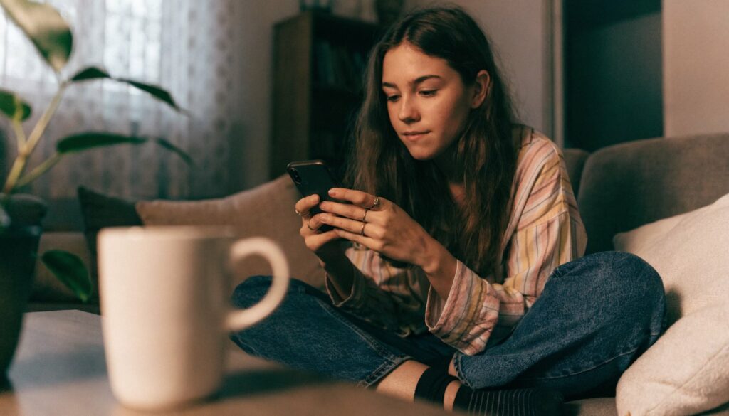 Jeune femme consultant son téléphone sur un canapé