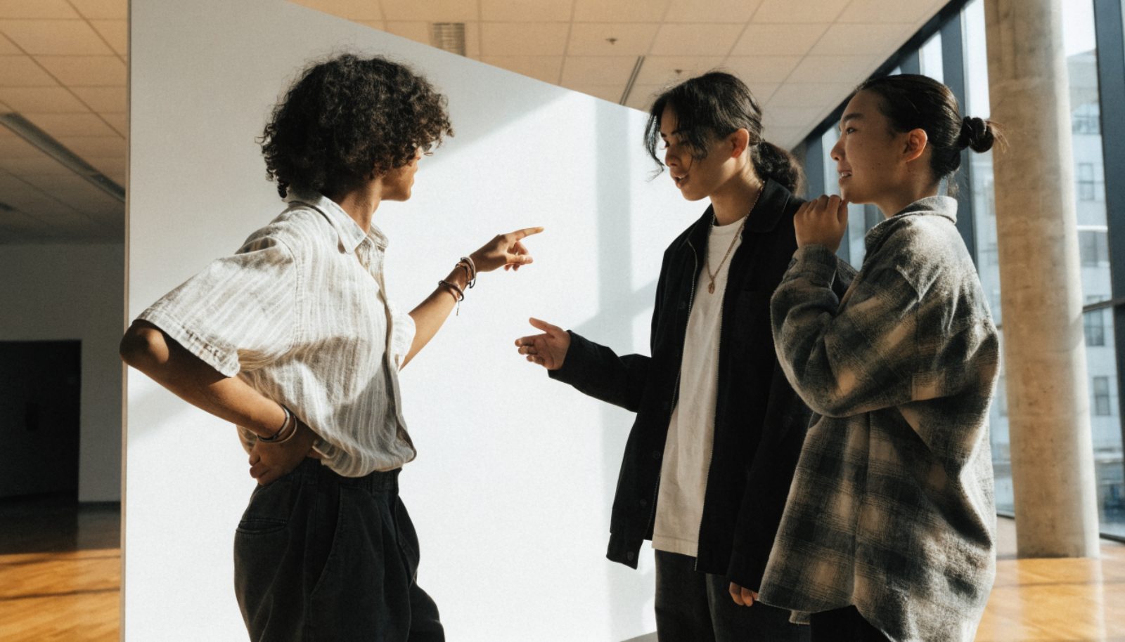 Trois jeunes devant un panneau d'information dans un hall de salon